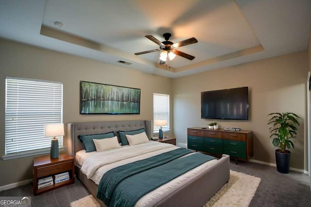 carpeted bedroom with a tray ceiling and ceiling fan