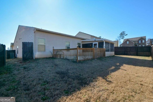 back of property featuring a sunroom, a yard, and a deck