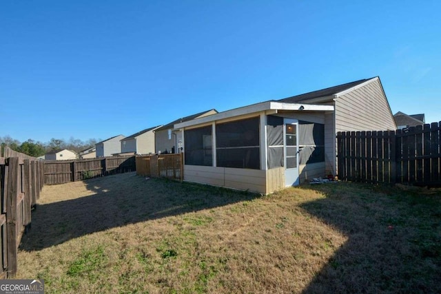 back of house featuring a lawn and a sunroom