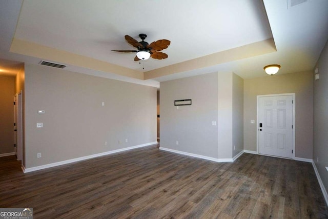 unfurnished room with dark hardwood / wood-style floors, ceiling fan, and a tray ceiling