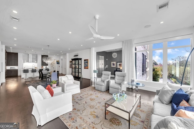 living room featuring dark hardwood / wood-style floors and ceiling fan with notable chandelier