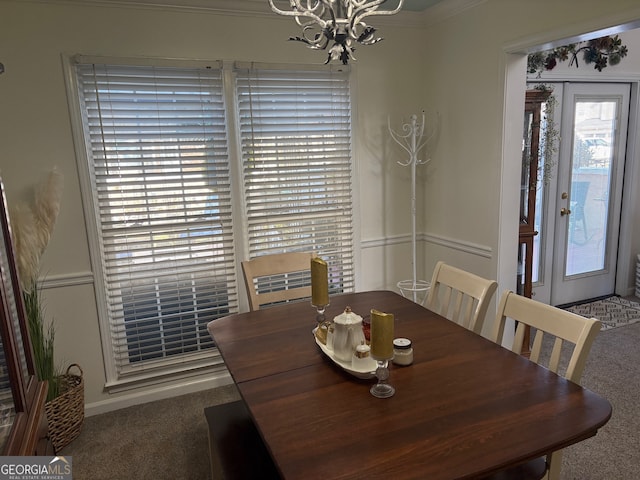 dining area with carpet floors, crown molding, and a notable chandelier