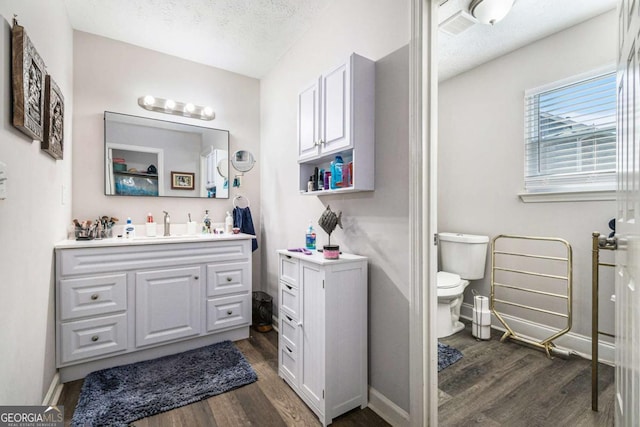 bathroom with vanity, toilet, wood-type flooring, and a textured ceiling