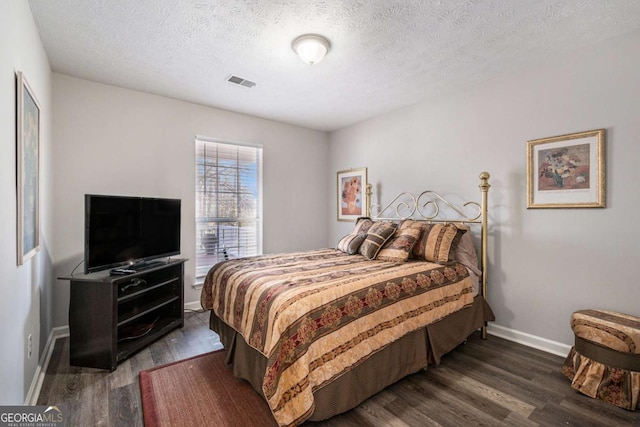 bedroom with a textured ceiling and dark hardwood / wood-style floors