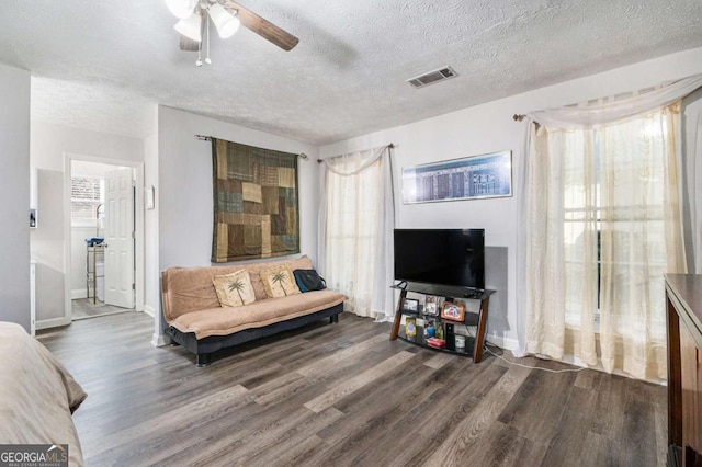 living room with a textured ceiling, dark hardwood / wood-style flooring, and ceiling fan