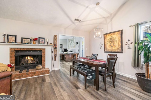 1276 Westover Trce NW, Acworth, GA 30102 - dining room featuring wood finished floors, a brick fireplace, lofted ceiling, and a chandelier