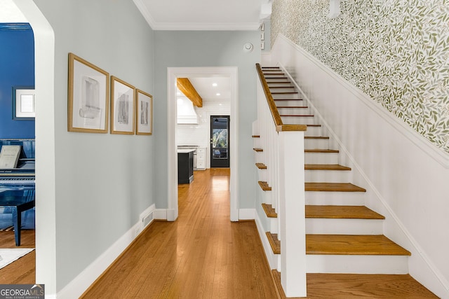 stairs featuring wood-type flooring and crown molding