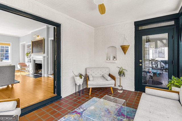 living area with dark tile patterned flooring, ceiling fan, and crown molding