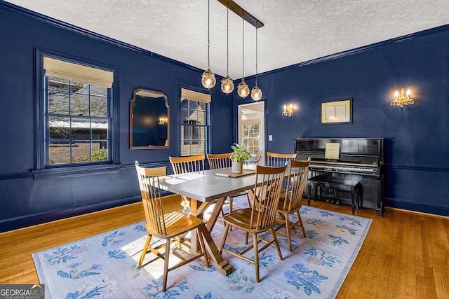 dining room featuring hardwood / wood-style floors, a textured ceiling, and ornamental molding