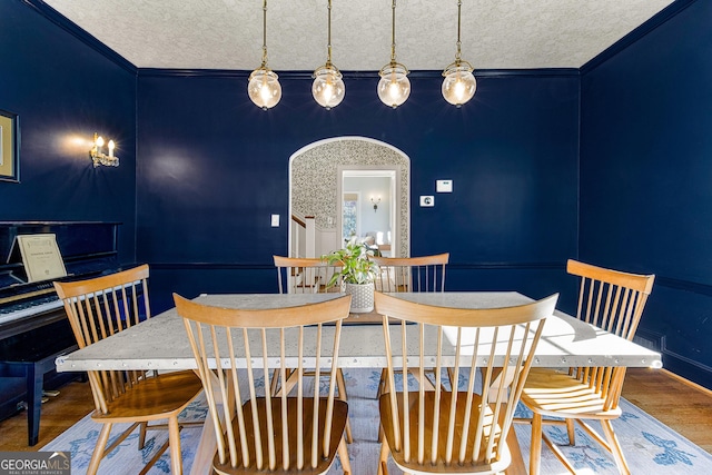 dining room featuring a textured ceiling, hardwood / wood-style flooring, and ornamental molding