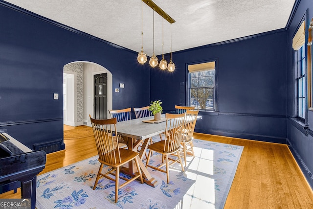 dining area featuring a textured ceiling, light hardwood / wood-style flooring, and ornamental molding