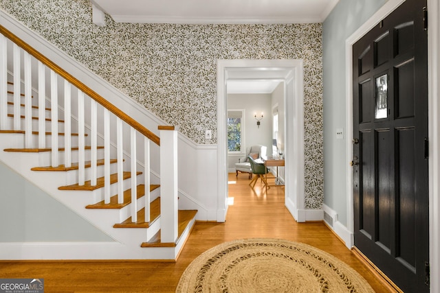 foyer featuring wood-type flooring and crown molding