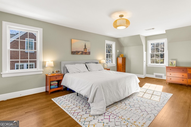 bedroom with light wood-type flooring and vaulted ceiling