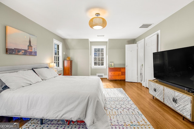 bedroom with light hardwood / wood-style floors and lofted ceiling