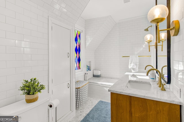 bathroom featuring tiled bath, vanity, tile walls, and toilet