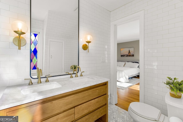 bathroom featuring tile patterned floors, vanity, toilet, and tile walls