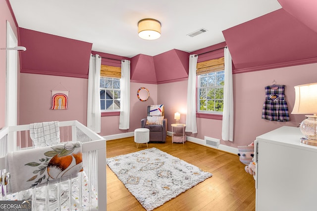 bedroom with hardwood / wood-style floors and a nursery area