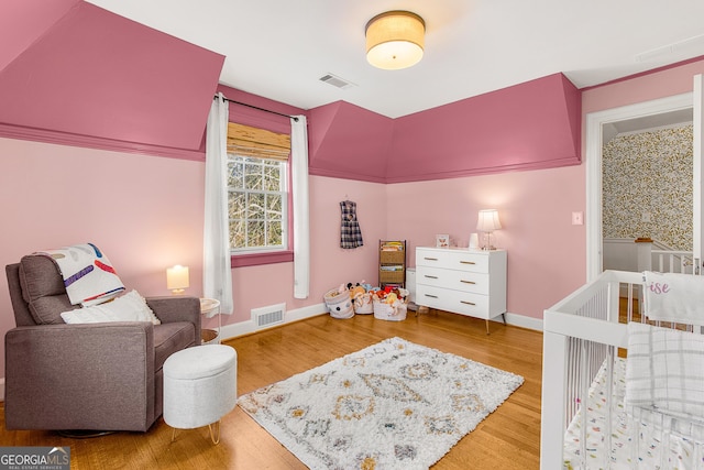 bedroom featuring hardwood / wood-style floors and a nursery area