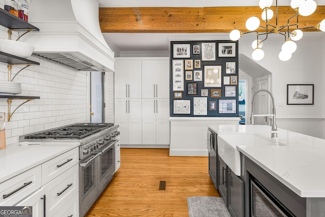 kitchen with premium range hood, white cabinetry, hanging light fixtures, and double oven range