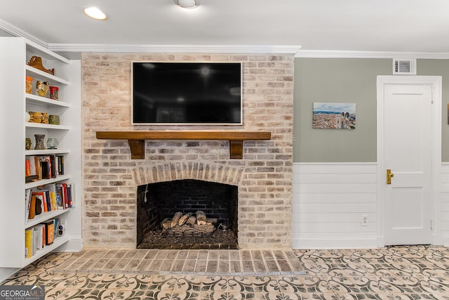 living room with built in shelves, ornamental molding, and a brick fireplace