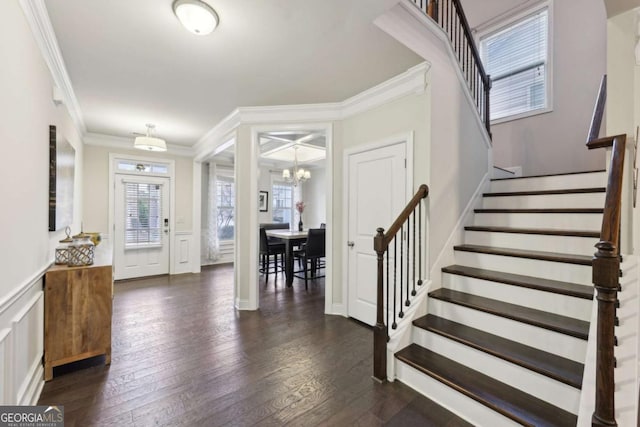 entryway featuring dark hardwood / wood-style floors, crown molding, and an inviting chandelier