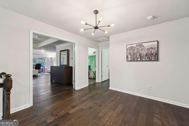 empty room with dark hardwood / wood-style floors and a chandelier