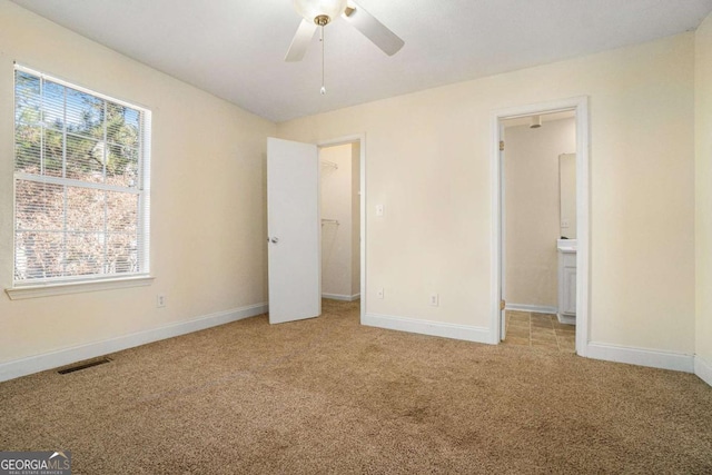 unfurnished bedroom featuring ceiling fan, a closet, carpet, and ensuite bathroom