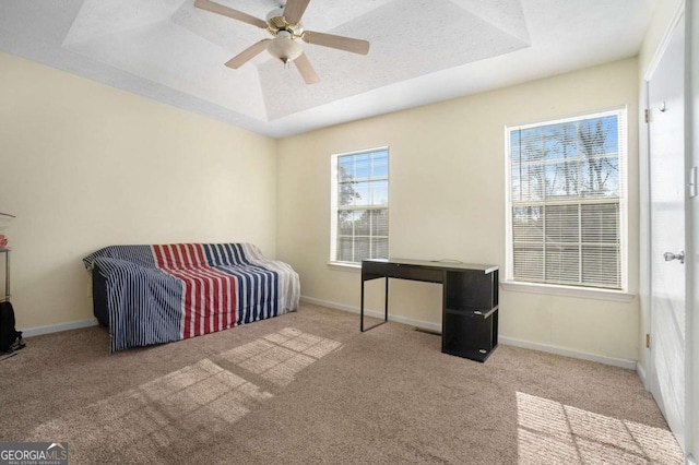 bedroom featuring a textured ceiling, ceiling fan, a raised ceiling, and light carpet