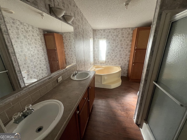 bathroom with tasteful backsplash, hardwood / wood-style floors, a textured ceiling, vanity, and independent shower and bath