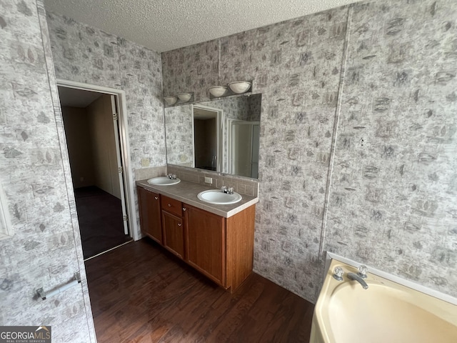 bathroom with hardwood / wood-style floors, vanity, a bath, and a textured ceiling