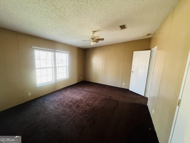 carpeted empty room featuring ceiling fan and a textured ceiling