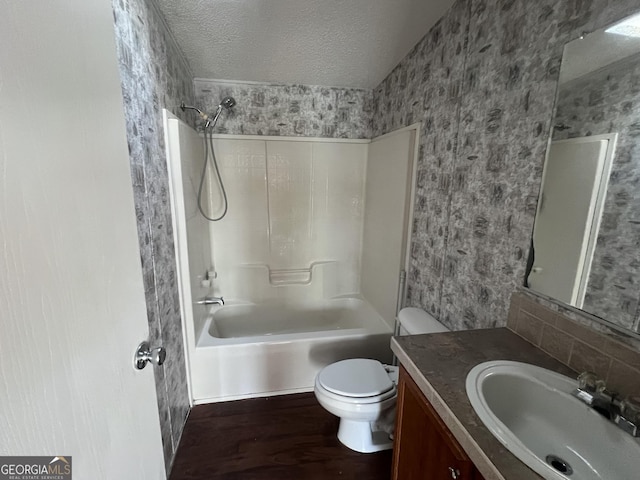 full bathroom featuring vanity, a textured ceiling, bathing tub / shower combination, hardwood / wood-style floors, and toilet