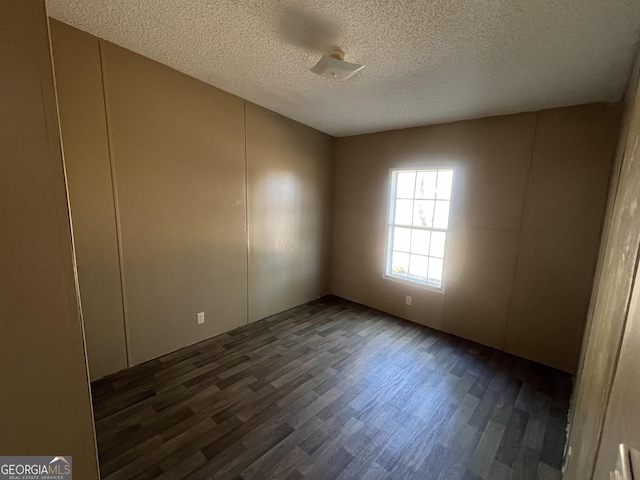 spare room featuring a textured ceiling and dark wood-type flooring