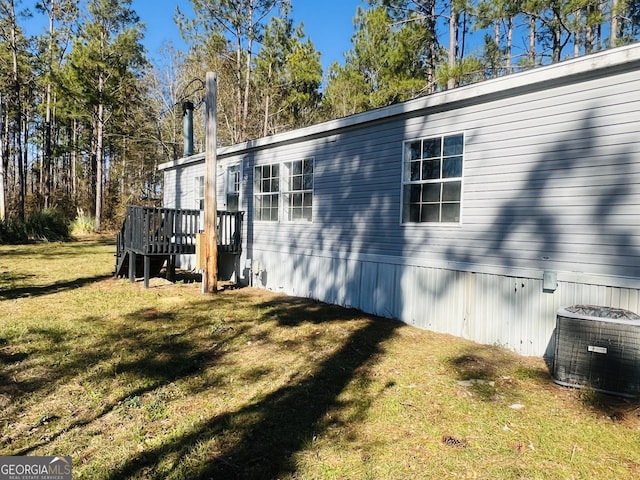 view of side of property featuring cooling unit, a deck, and a yard