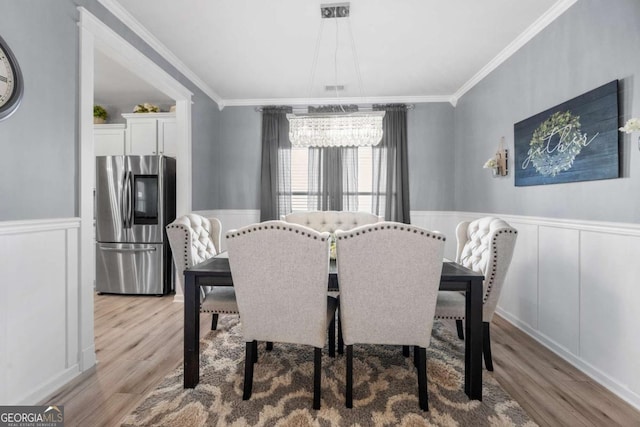 dining area featuring crown molding, light hardwood / wood-style floors, and a notable chandelier