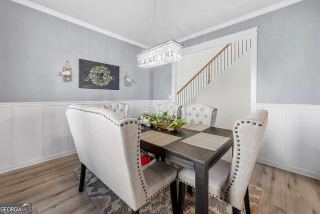 dining space featuring light hardwood / wood-style floors, ornamental molding, and a notable chandelier