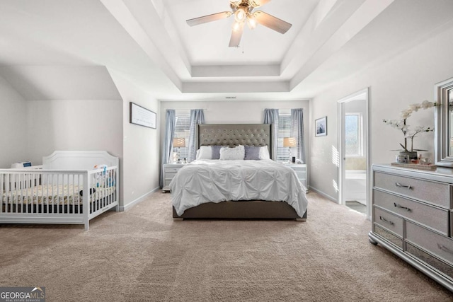 bedroom with ceiling fan, multiple windows, light carpet, and a tray ceiling