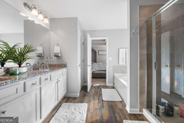 bathroom featuring plus walk in shower, vanity, and wood-type flooring