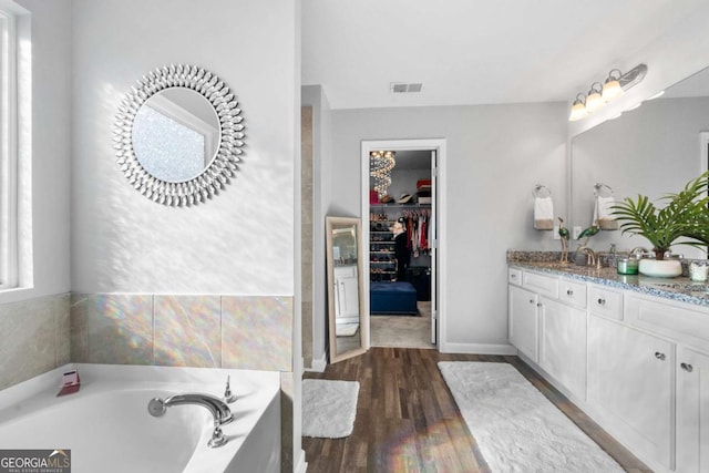 bathroom with hardwood / wood-style flooring, vanity, and a tub to relax in