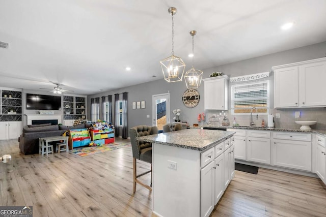 kitchen featuring a breakfast bar area, white cabinetry, a center island, and sink