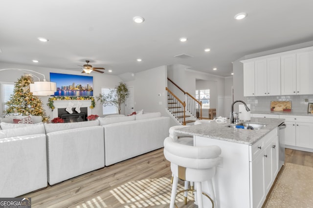 kitchen with a glass covered fireplace, light wood-style flooring, open floor plan, and a sink