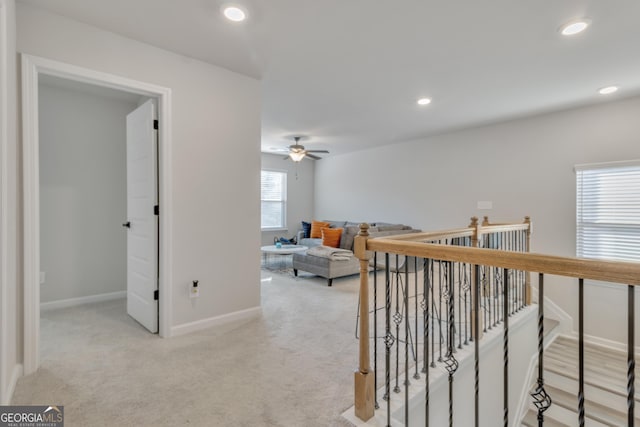 corridor featuring recessed lighting, an upstairs landing, baseboards, and light carpet