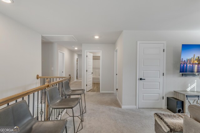 interior space with recessed lighting, light colored carpet, attic access, and baseboards