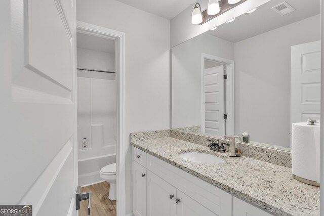 full bathroom featuring vanity, wood finished floors, visible vents, bathing tub / shower combination, and toilet