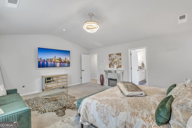 bedroom with visible vents, lofted ceiling, carpet, and a glass covered fireplace