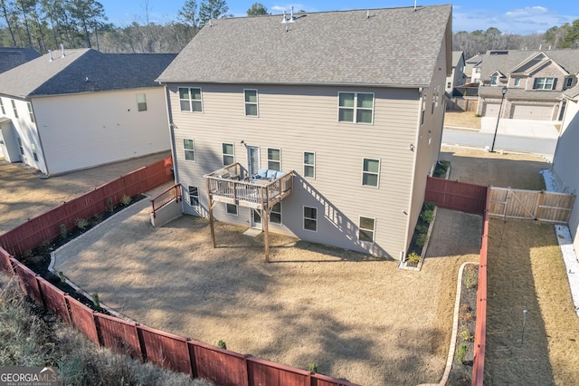 rear view of property featuring a residential view, a wooden deck, a fenced backyard, and roof with shingles