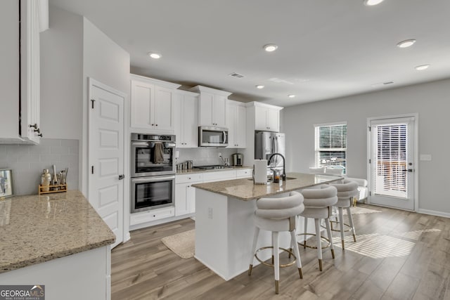 kitchen featuring white cabinetry, light wood-style flooring, a breakfast bar, and stainless steel appliances