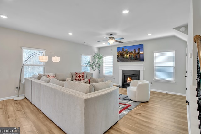 living room with light wood finished floors, baseboards, ceiling fan, a fireplace with flush hearth, and recessed lighting