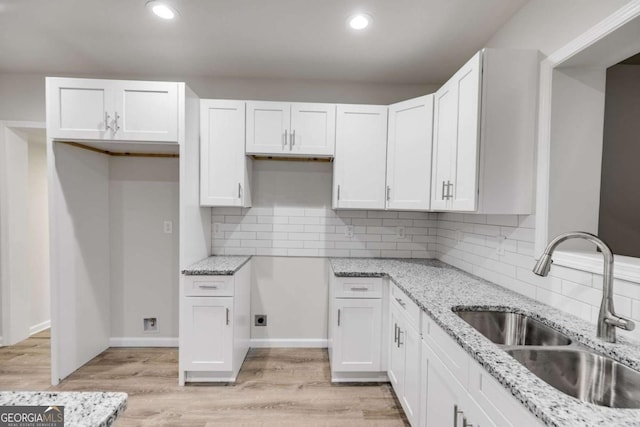 kitchen featuring decorative backsplash, light stone counters, white cabinetry, and sink