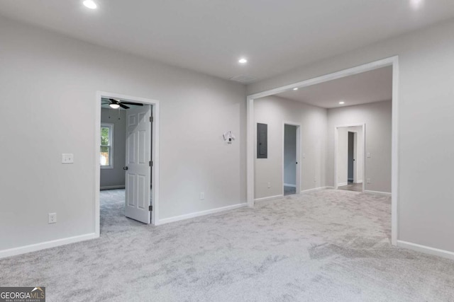 spare room with light carpet, electric panel, and ceiling fan